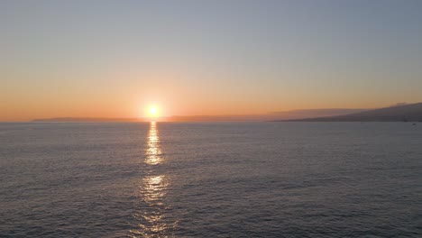Filmische-Antenne---Sonnenaufgangsreflexion-über-Dem-Ozean-Mit-Pico-Insel-Am-Horizont