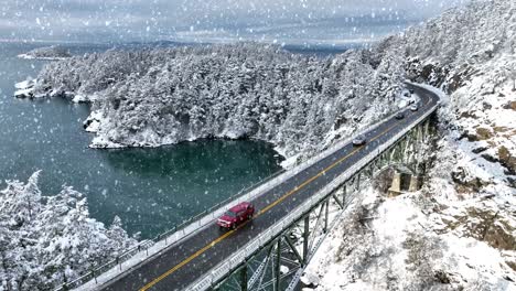 Cars-driving-across-Deception-Pass-bridge-with-snow-falling-and-covering-the-ground