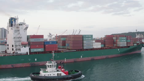Tug-boat-escorting-a-large-container-ship-out-of-Durban-harbour,-South-Africa