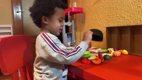 Zweijähriges-Schwarzes-Baby,-Mischling,-Spielt-Zu-Hause,-Um-Das-Essen-In-Seiner-Spielzeugküche-Zuzubereiten