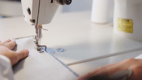 Person-is-using-sewing-machine-to-fix-and-sew-peace-of-white-cotton-clothing