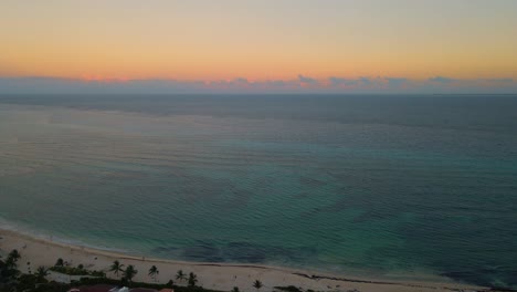 Aerial-view-of-the-tropical-ocean-pulling-away-to-reveal-the-land-of-Mexico's-coast-during-golden-hour