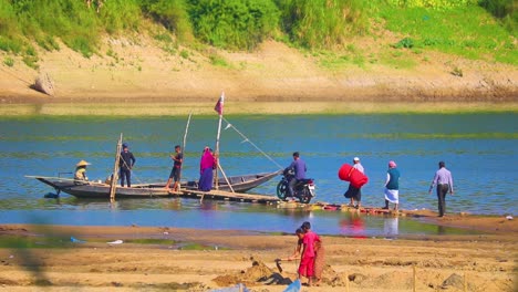 People-boarding-wooden-boat-for-river-crossing,-handheld-view