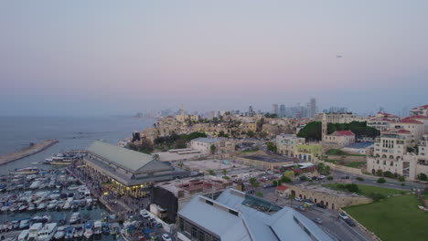 Luftaufnahme-Von-Vorne-über-Die-Altstadt-Und-Den-Hafen-Von-Jaffa-Zur-Skyline-Von-Tel-Aviv-Bei-Sonnenuntergang---Langsames-Hineinschieben