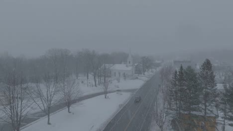 A-truck-drives-out-of-Monson-Town-during-snowfall-Aerial-Slow-motion