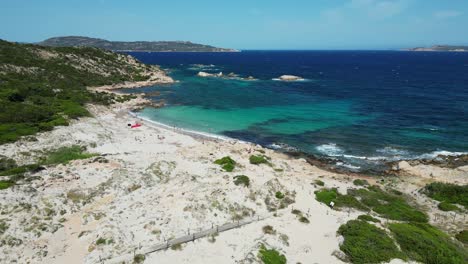 Tourist-people-relax-and-swim-at-white-sandy-beach-at-La-Maddalena-Island,-Sardinia---Aerial-4k