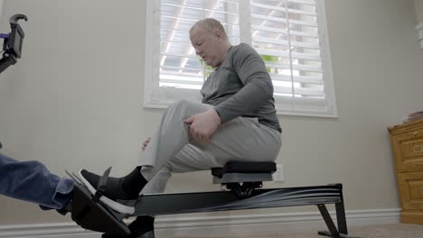Senior-man-gets-on-a-rowing-machine-for-exercise---sliding-motion