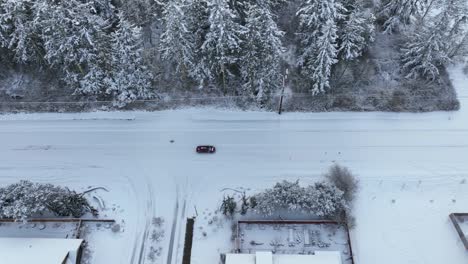 Aerial-view-of-a-car-carefully-driving-on-fresh-snow
