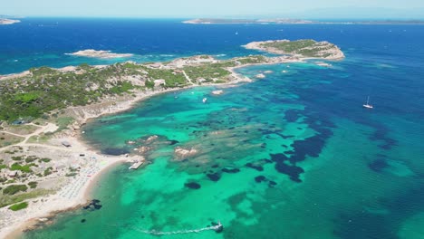 Windsurfer-sails-at-turquoise-blue-sea-along-coastline-of-La-Maddalena-Island,-Sardinia---Aerial