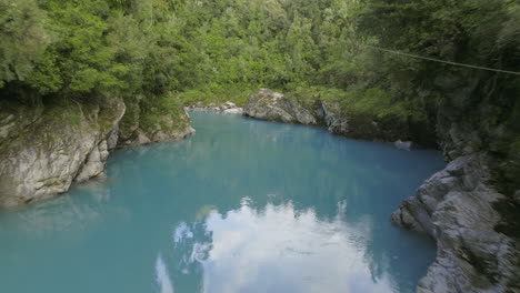 Serene-dreamy-azure-hue-Hokitika-River-carved-through-granite-rock,-aerial