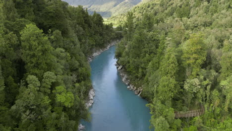 Magical-glacial-blue-meltwater-flowing-through-Hokitika-Gorge,-aerial