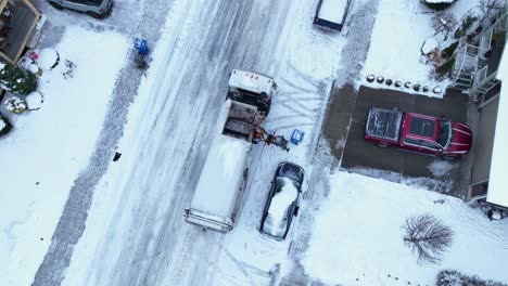 Overhead-aerial-view-of-a-garbage-truck-picking-up-trash-in-snow-conditions