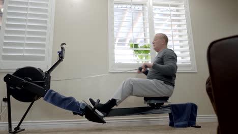 Senior-overweight-man-exercising-on-a-rowing-machine-at-home