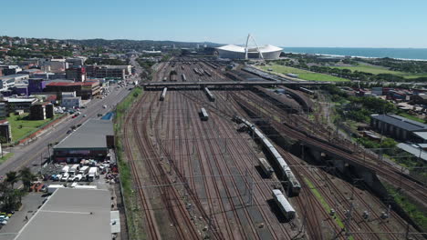 Luftdrohnenaufnahme-Des-Bahnhofs-Von-Durban-Mit-Dem-Moses-Mabhida-Stadion-Im-Hintergrund-Und-Dem-Indischen-Ozean