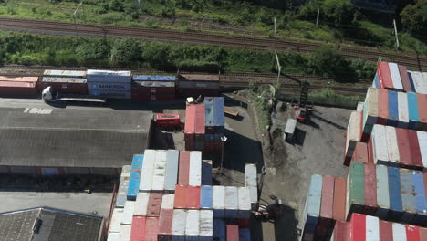 Aerial-drone-shot-of-Trucks-driving-into-a-shipping-container-yard