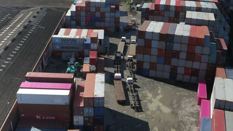 Aerial-drone-shot-of-empty-trucks-waiting-to-be-loaded-inside-a-shipping-container-yard