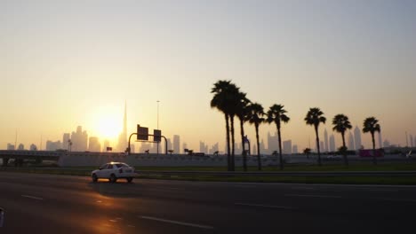 Dubai-Skyline-Bei-Sonnenuntergang-Gesehen-Von-Einem-Fahrenden-Auto-Mit-Hintergrundbeleuchteter-Skyline-Der-Stadt