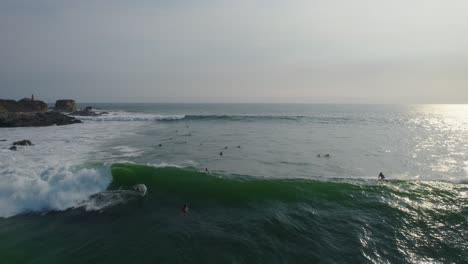 Aerial-view-surfers-riding-powerful-wave-on-Punta-Zicatela-sunlit-Pacific-ocean-Oaxaca-seascape