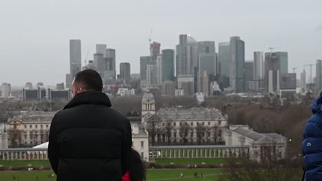 View-from-Greenwich-Park-of-people-looking-towards-Canary-Wharf-on-a-cloudy-day,-London,-United-Kingdom