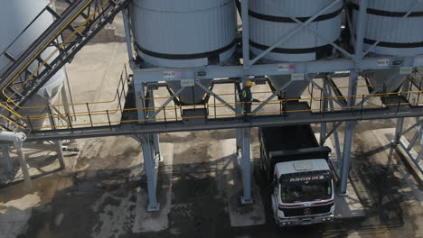 Aerial-drone-shot-of-a-construction-truck-being-loaded-with-hot-asphalt-at-an-asphalt-production-plant