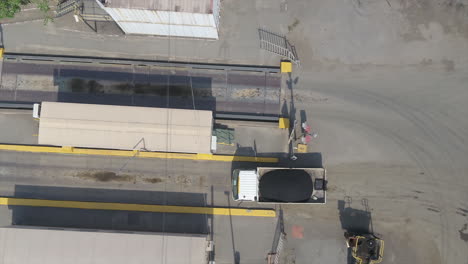 Aerial-drone-shot-of-a-truck-loaded-with-asphalt-driving-onto-a-weigh-bridge
