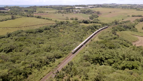 Aerial-drone-shot-of-a-passenger-train-in-South-Africa-traveling-through-green-hills