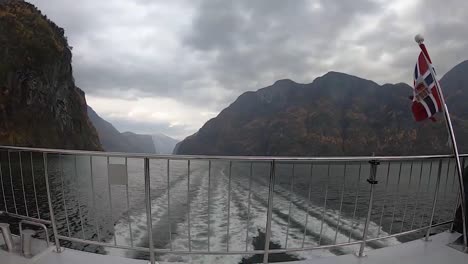 Timelapse-rear-view-of-ship-with-Norwegian-flag-sailing-through-the-Norwegian-fjords