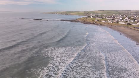 Waves-foaming-and-crushing-on-sandy-beach-in-slow-motion,-an-aerial-footage-during-winter-morning-in-Ireland