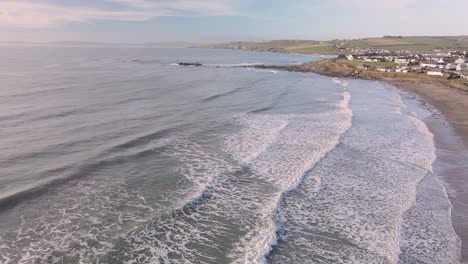 Vast-winter-ocean-and-coastal-countryside-with-slow-motion-waves-from-above