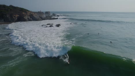 Aerial-tracking-shot-of-a-surfer-completing-acrobatic-turns-and-riding-a-wave