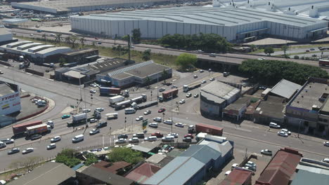 Drone-onto-busy-intersection-with-traffic-and-trucks-in-an-industrial-area-of-Durban,-South-Africa