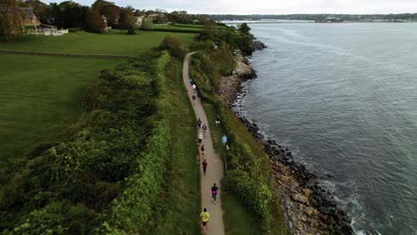 Aerial-of-runners-running-on-a-path-next-to-the-ocean