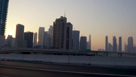 Conduciendo-Por-Las-Carreteras-De-Dubai-Al-Atardecer-Con-El-Horizonte-Retroiluminado