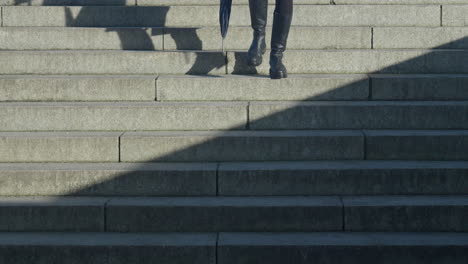 Woman-in-black-boots-walking-down-stone-steps-casting-a-shadow