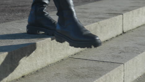 Black-woman's-boots-walking-down-grey-stone-steps