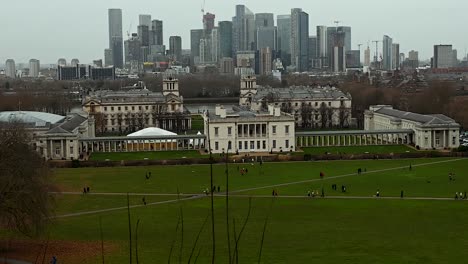 People-walking-within-Greenwich-Park-with-Canary-Wharf-behind,-London,-United-Kingdom