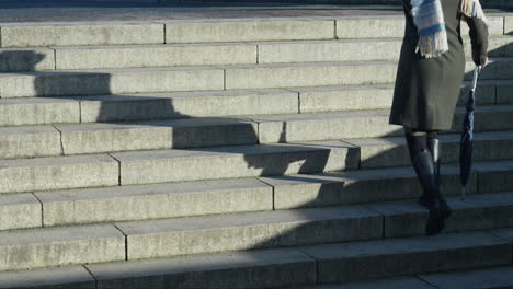 Woman-walking-up-stone-steps-casting-a-long-shadow
