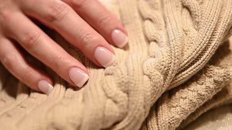 luxurious-French-manicure-finger-nails-resting-on-a-tan-luxury-sweater