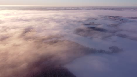 Flying-over-fog-mist-clouds-and-frost-covered-seasonal-forests-in-sunrise-light