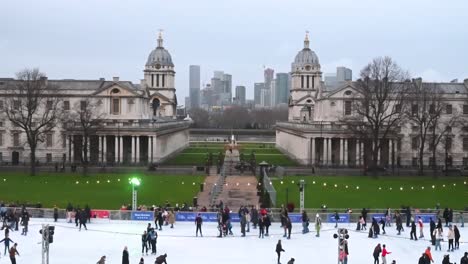 People-ice-skating-within-the-Old-Royal-Naval-College-Greenwich-in-front-of-Canary-Wharf,-London,-United-Kingdom