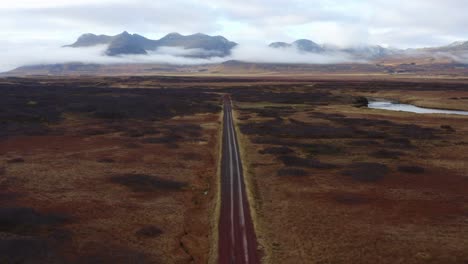 Drohnenvideo-Einer-Luftaufnahme-Einer-Straße,-Die-Durch-Die-Schwarze-Wüste-Mit-Einer-Majestätischen-Bergkette-In-Der-Isländischen-Landschaft-Führt:-Berühmte-Attraktionen-Und-Wahrzeichen-In-Der-Isländischen-Natur