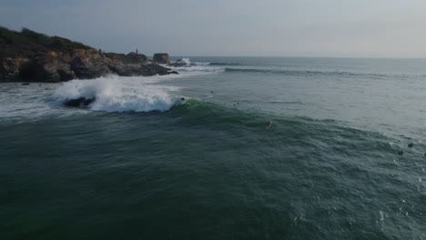 Aerial-view-following-surfers-riding-sunlit-waves-on-Punta-Zicatela-Oaxaca-Pacific-ocean-seascape