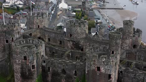 Historic-Conwy-castle-aerial-view-of-Landmark-town-ruin-stone-wall-battlements-tourist-attraction-close-orbit-right