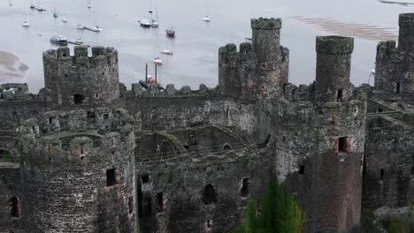 Historic-Conwy-castle-aerial-view-of-Landmark-town-ruin-stone-wall-battlements-tourist-attraction-orbit-rising-right