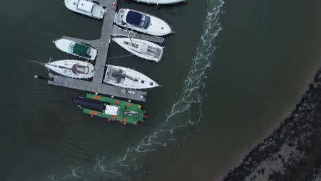 Top-down-aerial-drone-view-following-wake-trail-above-luxury-moored-private-marina-sailing-ships-and-yacht-boats