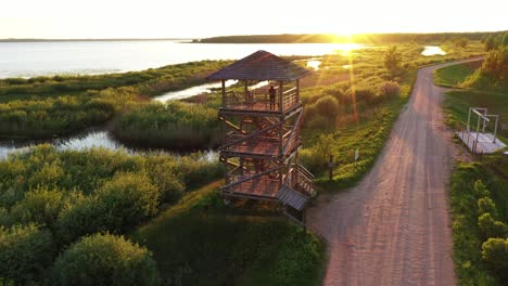 Beautiful-woman-enjoy-majestic-landscape-from-wooden-lookout-tower-during-golden-sunset
