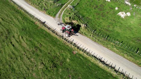 Red-tractor-driving-on-gravel-road-in-rural-setting