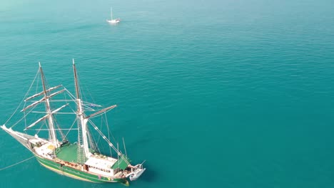 Sailing-ship-sails-in-a-wonderful-crystal-clear-sea,-aerial-view-from-drone-at-Whitsunday
