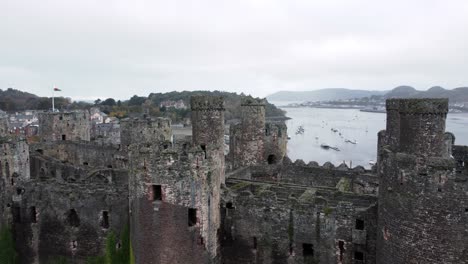 Historic-Conwy-castle-aerial-view-of-Landmark-town-ruin-stone-wall-battlements-tourist-attraction-low-left-dolly
