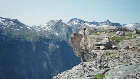 Man-Walking-Towards-Rocky-Cliff-In-The-Katthammaren-Mountains-In-Norway---wide-shot